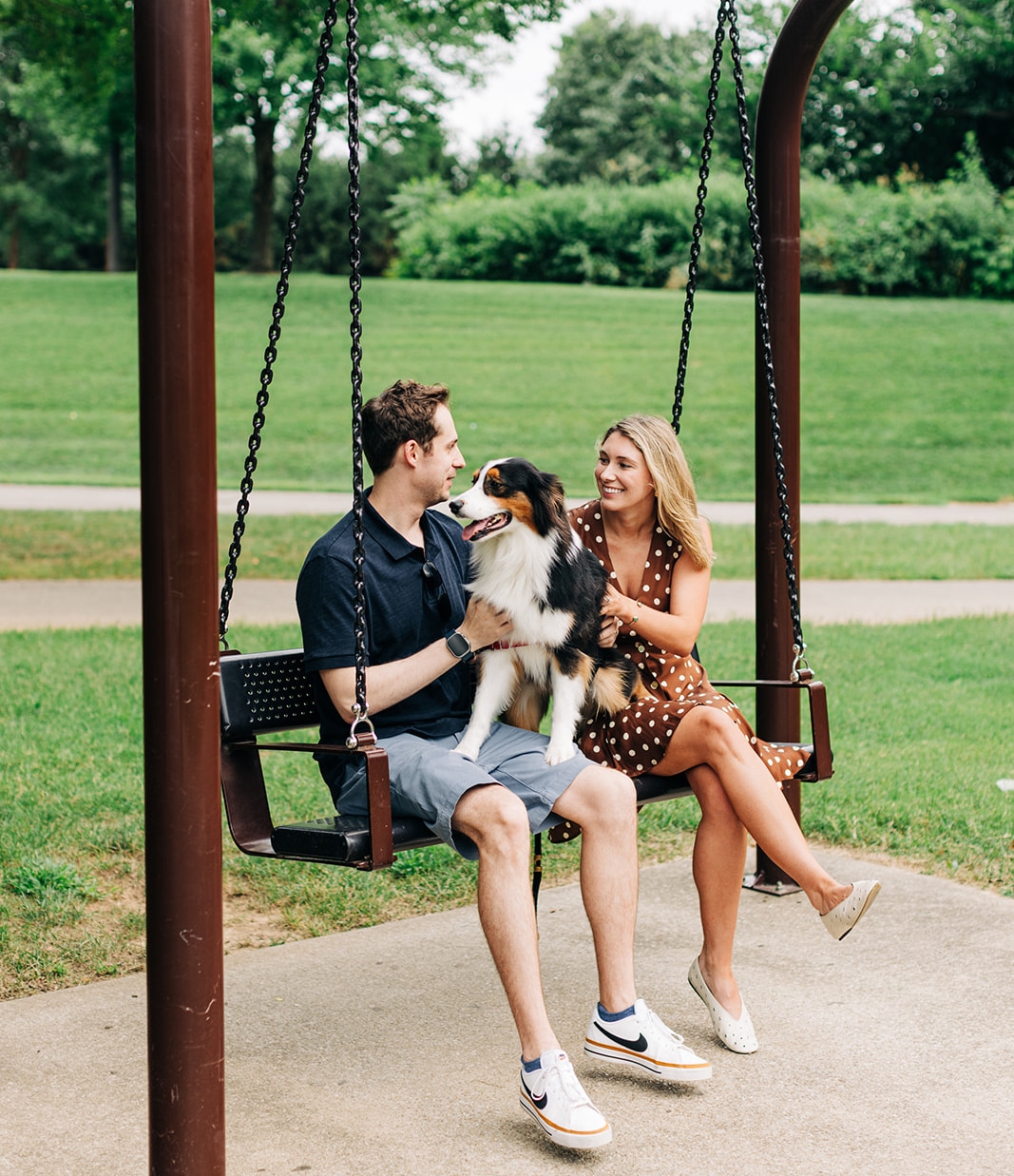 couple and dog on a swing at the park